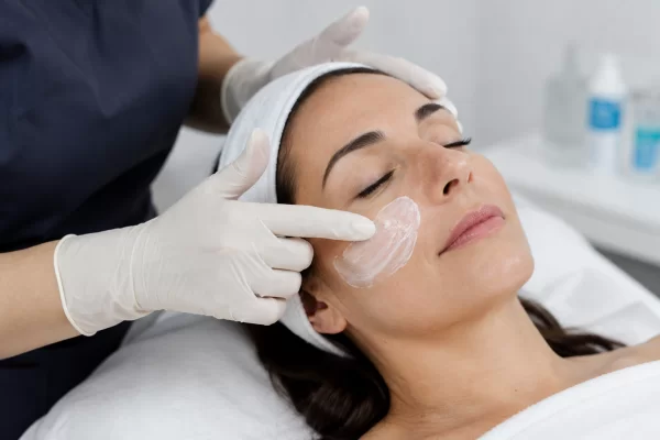 Clinician applying topical numbing cream to a patient's cheek before a platelet-rich plasma treatment session